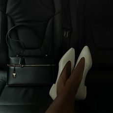 Jasmine Tookes wearing white Loro Piana Rebecca flats and a handbag in a car.