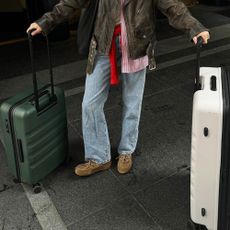 Woman with suitcases wearing jeans and Miu Miu boat shoes